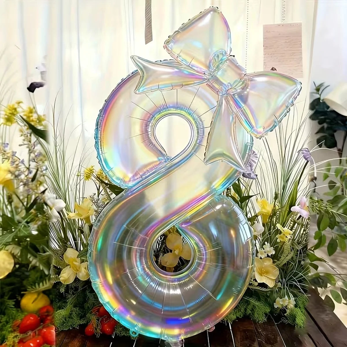 A bouquet of yellow and white flowers is surrounded by large, iridescent, transparent number balloons shaped like the number 