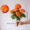 Una mano sostiene una rama de geranios de seda artificial rojos con hojas verdes, mostrando el tamaño y detalle.