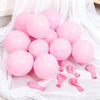 A collection of pink latex balloons and pink ribbon streamers laid out on white fabric.
