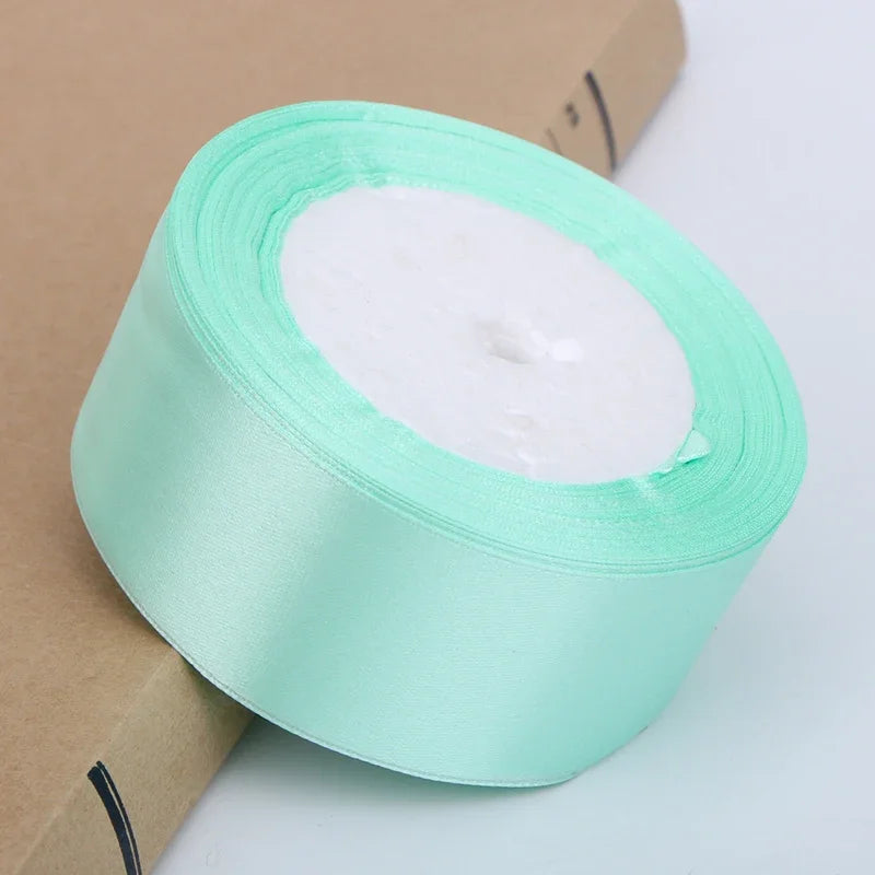 Roll of light mint green satin ribbon with white wax inside for crafts and gift wrapping