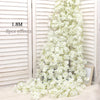 A long vertical arrangement of white artificial sakura flowers displayed against a light wooden slat background.