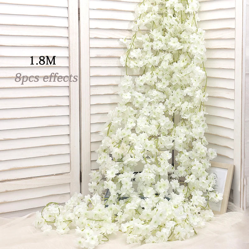 A long vertical arrangement of white artificial sakura flowers displayed against a light wooden slat background.