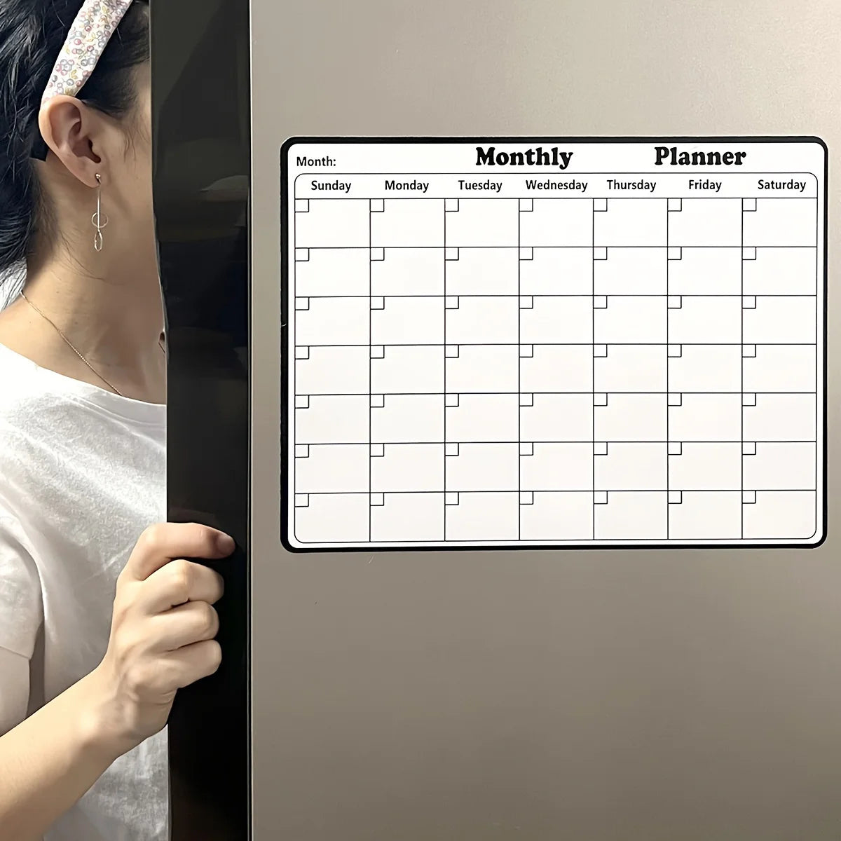 A monthly planner calendar displayed on a refrigerator door, showing days of the week and grid lines.