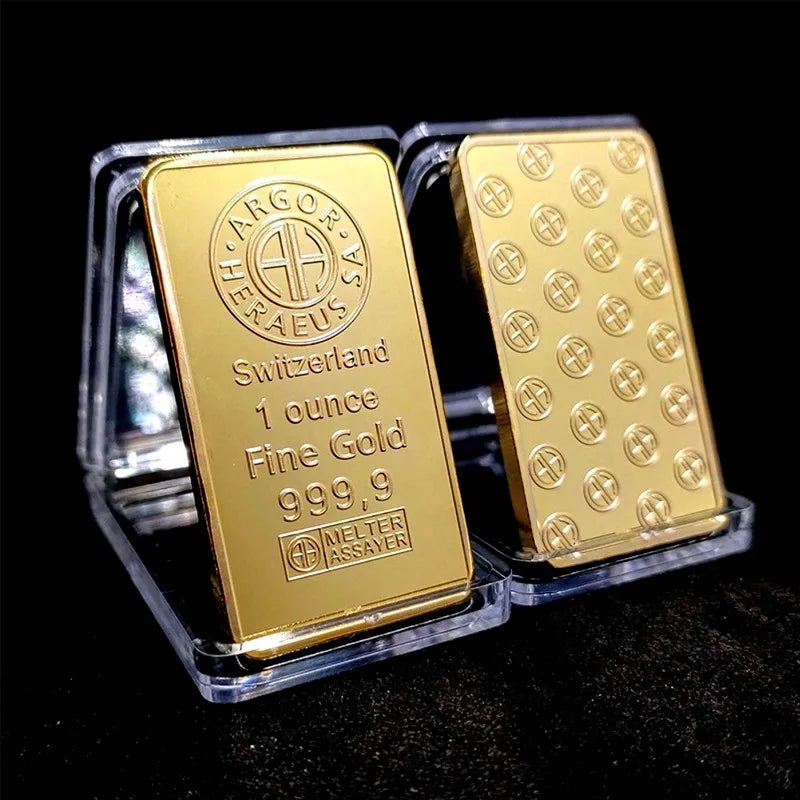 A rectangular gold plated bullion ingot labeled ARGOR HERAEUS Switzerland 1 ounce Fine Gold 999.9 inside a clear plastic hold