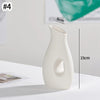 A white minimalist ceramic vase with a smooth, elongated shape is shown on a white surface.