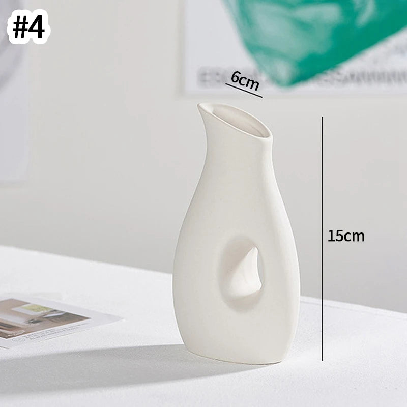 A white minimalist ceramic vase with a smooth, elongated shape is shown on a white surface.