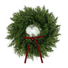 A 10-inch artificial Christmas wreath made of green foliage with a red velvet bow.