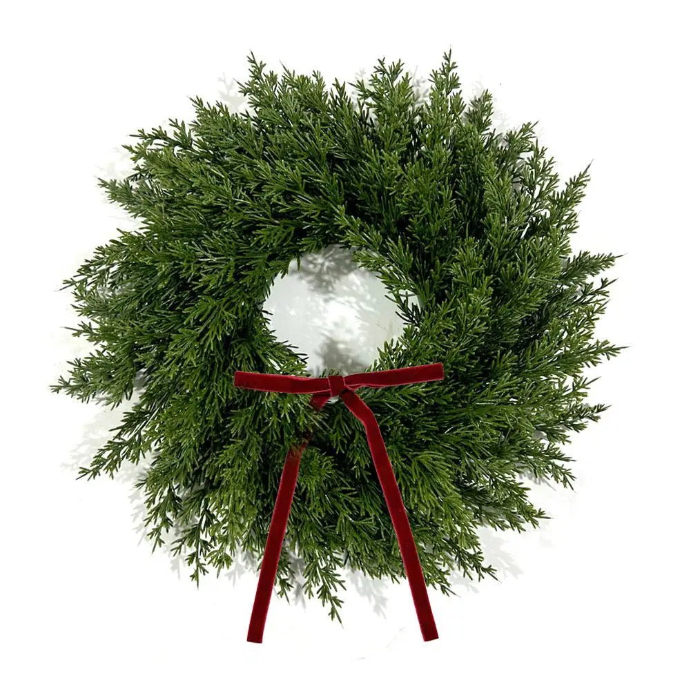 A 10-inch artificial Christmas wreath made of green foliage with a red velvet bow.
