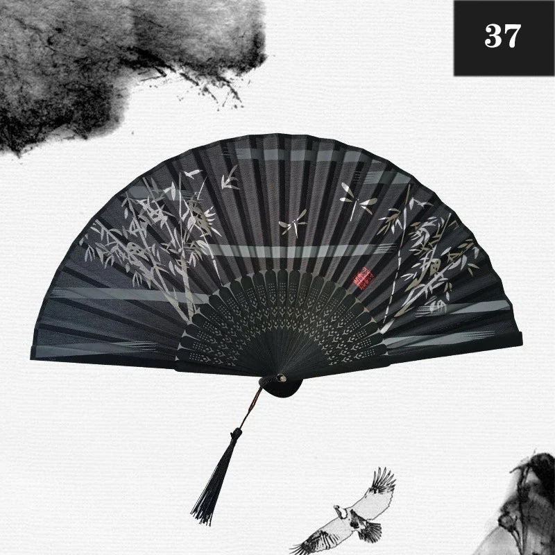 A black and gray vintage silk bamboo folding hand fan with a radial pattern and a small bird detail.