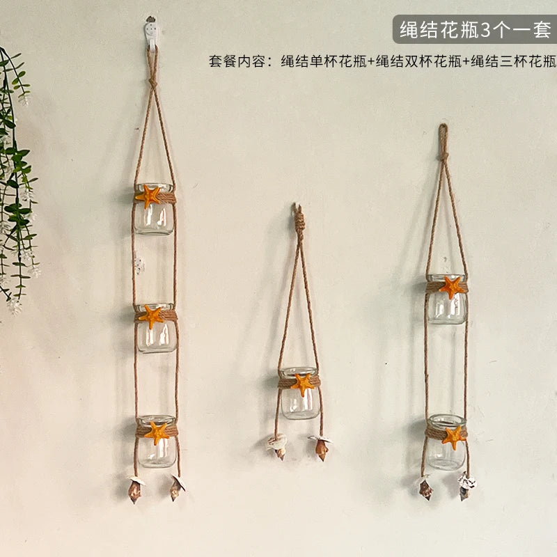 Three sets of hanging glass terrariums with small orange flowers and leaves