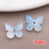 Un juego de 30 cuentas de mariposa azules transparentes en un fondo neutro.