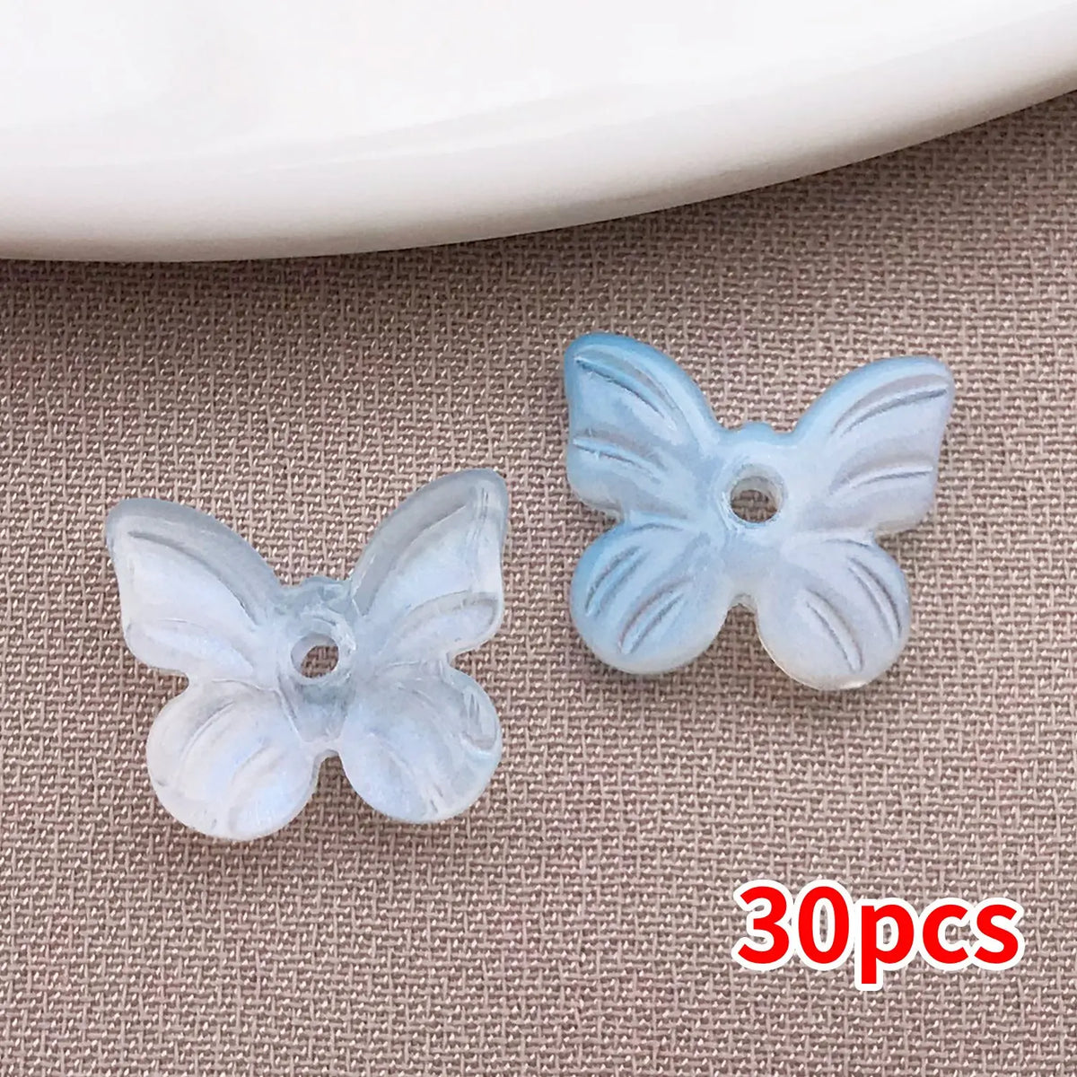 Un juego de 30 cuentas de mariposa azules transparentes en un fondo neutro.
