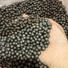 A hand is holding a large pile of dark gray foam beads for crafting and decoration.