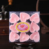 Un ensemble de bougies parfumées en forme de cœur roses emballées dans une boîte transparente.