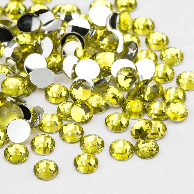 A pile of round, flatback resin rhinestones in yellow and clear colors.