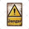 A vintage metal sign with a yellow triangle warning symbol and the word Danger on it.