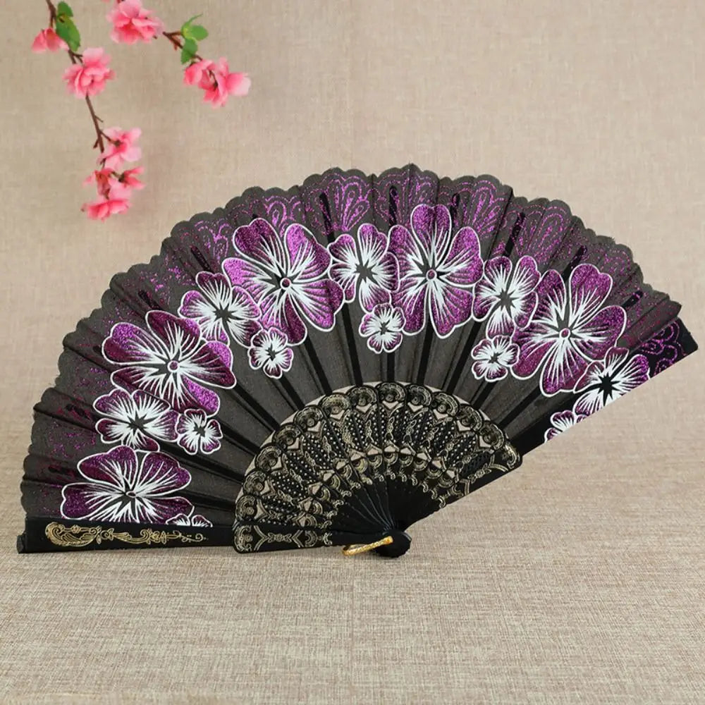A dark purple and white patterned bamboo flower antique folding fan displayed on a light beige surface.