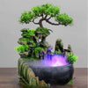 A resin waterfall desktop fountain featuring a mossy rock landscape and purple LED lighting.