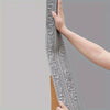 A hand is holding a long, decorative silver self-adhesive foam wall trim strip against a gray background.