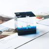 A clear acrylic box displaying a miniature resin landscape ornament of an elk deer silhouette against a blue background.