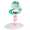 A PVC collectible figurine of Hatsune Miku in a white outfit with green hair and pink striped leg warmers.