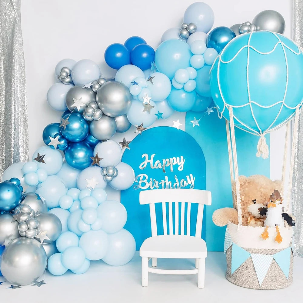 A cluster of blue and light blue latex balloons arranged around a white chair for a birthday party theme.