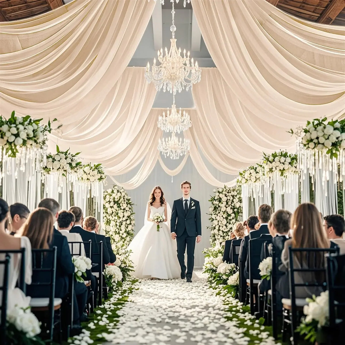 A wedding ceremony aisle decorated with white flowers and sheer fabric curtains leading to a couple.