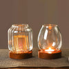 A vintage wooden candle lantern with a glass cover glowing warmly on a textured surface.