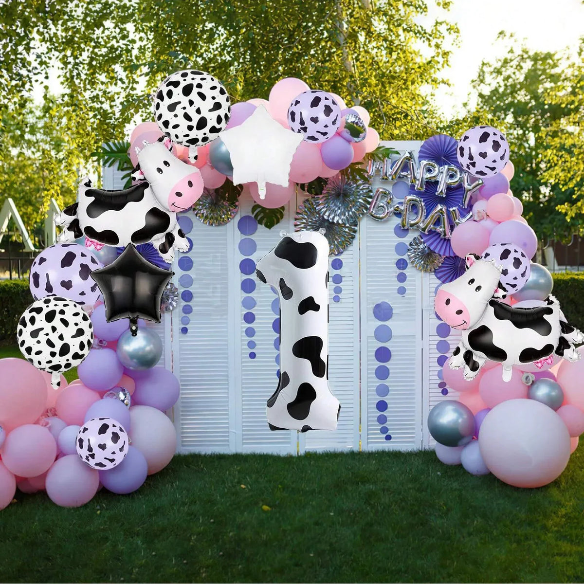 A colorful balloon arch decoration featuring cow print balloons and a large number one for a birthday party.