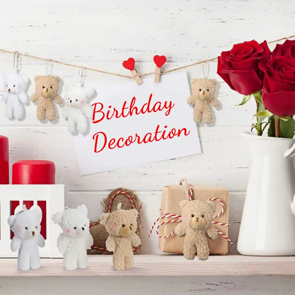 A birthday decoration featuring a string of plush teddy bear keychains and red roses on a white wooden background.