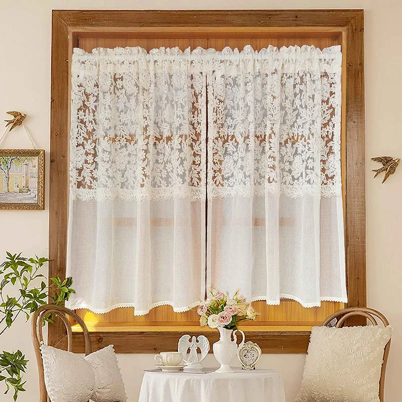 Beige sheer curtain with floral embroidery hanging in a wooden window frame.