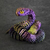 A detailed 3D printed rotatable snake art model with purple and yellow scales and a golden eye.