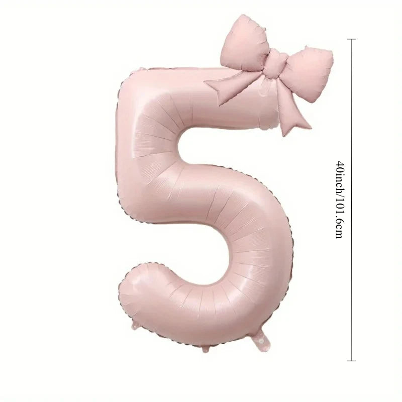 A large pink foil number balloon shaped like the number 5 with a bow.