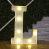 A glowing warm white LED alphabet letter light shaped like the letter L resting on a wooden surface.