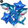 Five blue shark foil balloons and a number three balloon for an ocean-themed party decoration