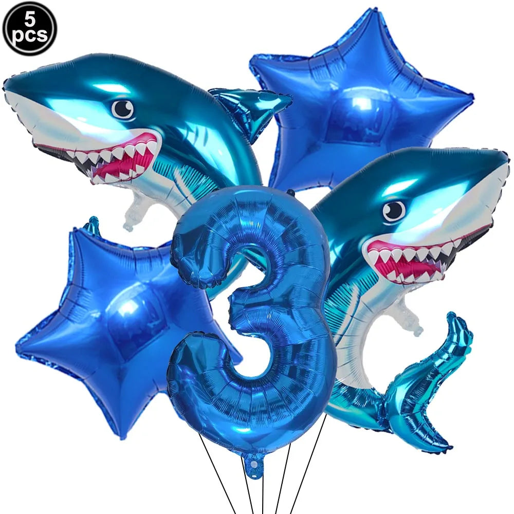 Five blue shark foil balloons and a number three balloon for an ocean-themed party decoration