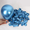 A hand holds a shiny blue football balloon and a pile of matching blue foil streamers.