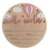 A natural wood birth announcement plaque featuring pink clouds, stars, and a pink hot air balloon with the text hello world.