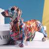 A colorful resin figurine of a dachshund dog standing on a white box.