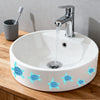 A white ceramic bathroom sink with blue sea turtle decals on the rim, next to a silver faucet and a toothbrush.