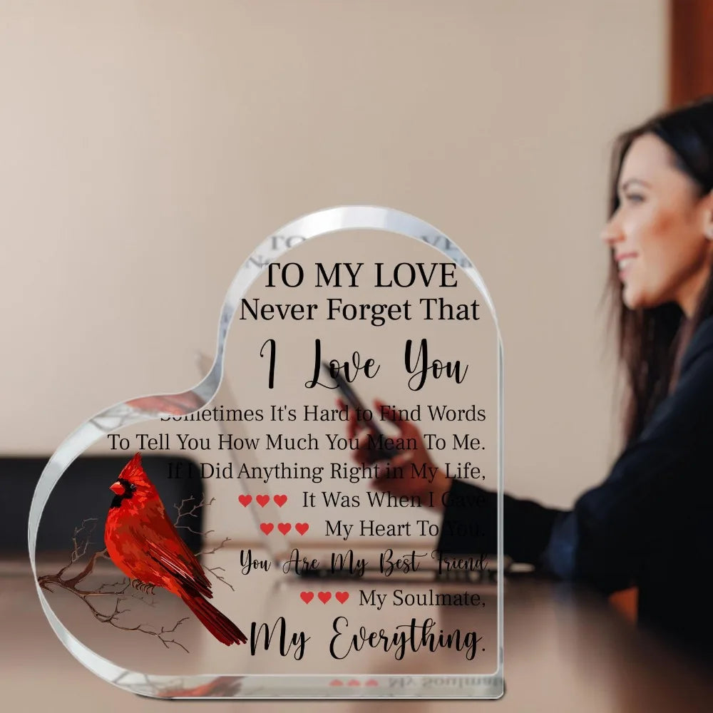 A heart-shaped acrylic plaque with a bird design and a handwritten love message on it.