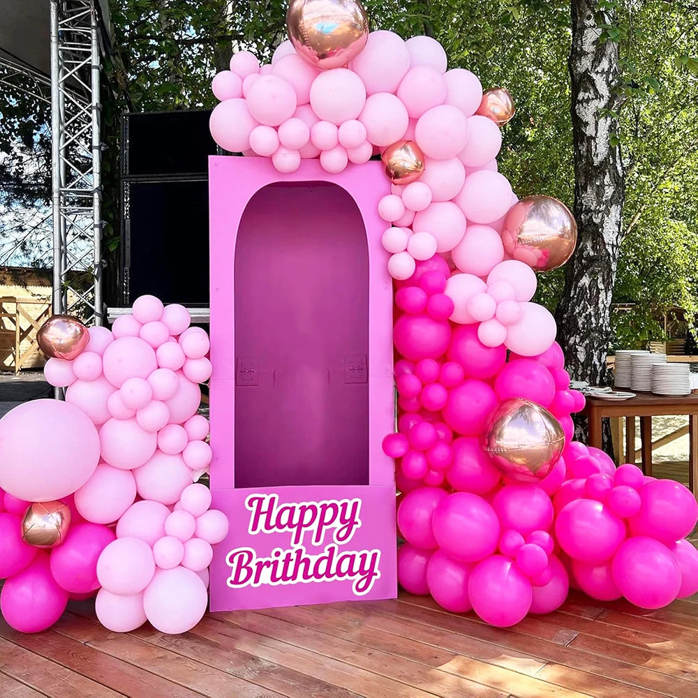 A large arrangement of pink and purple latex balloons forming a backdrop for a party event.