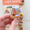 A hand holds a small brown guinea pig figure, part of an adorable refrigerator magnet set featuring various animals.