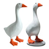 A pair of white and gray decorative resin goose figurines with orange beaks and feet.