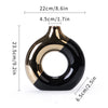 A black and gold ceramic flower vase with a rounded, organic shape.