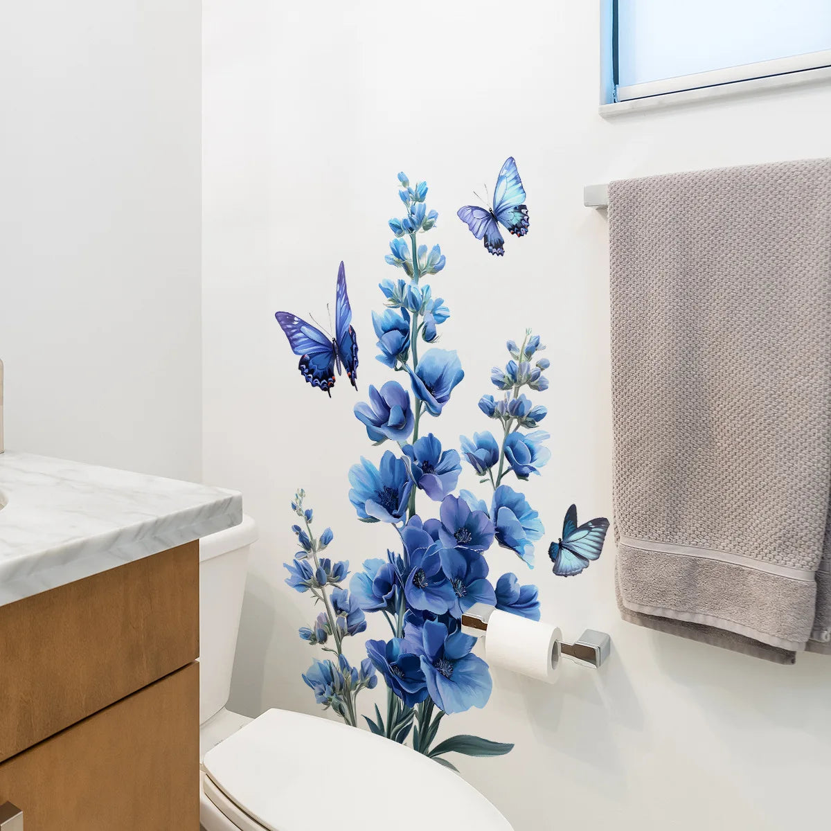 A white toilet area decorated with a blue flower and butterfly wall decal.