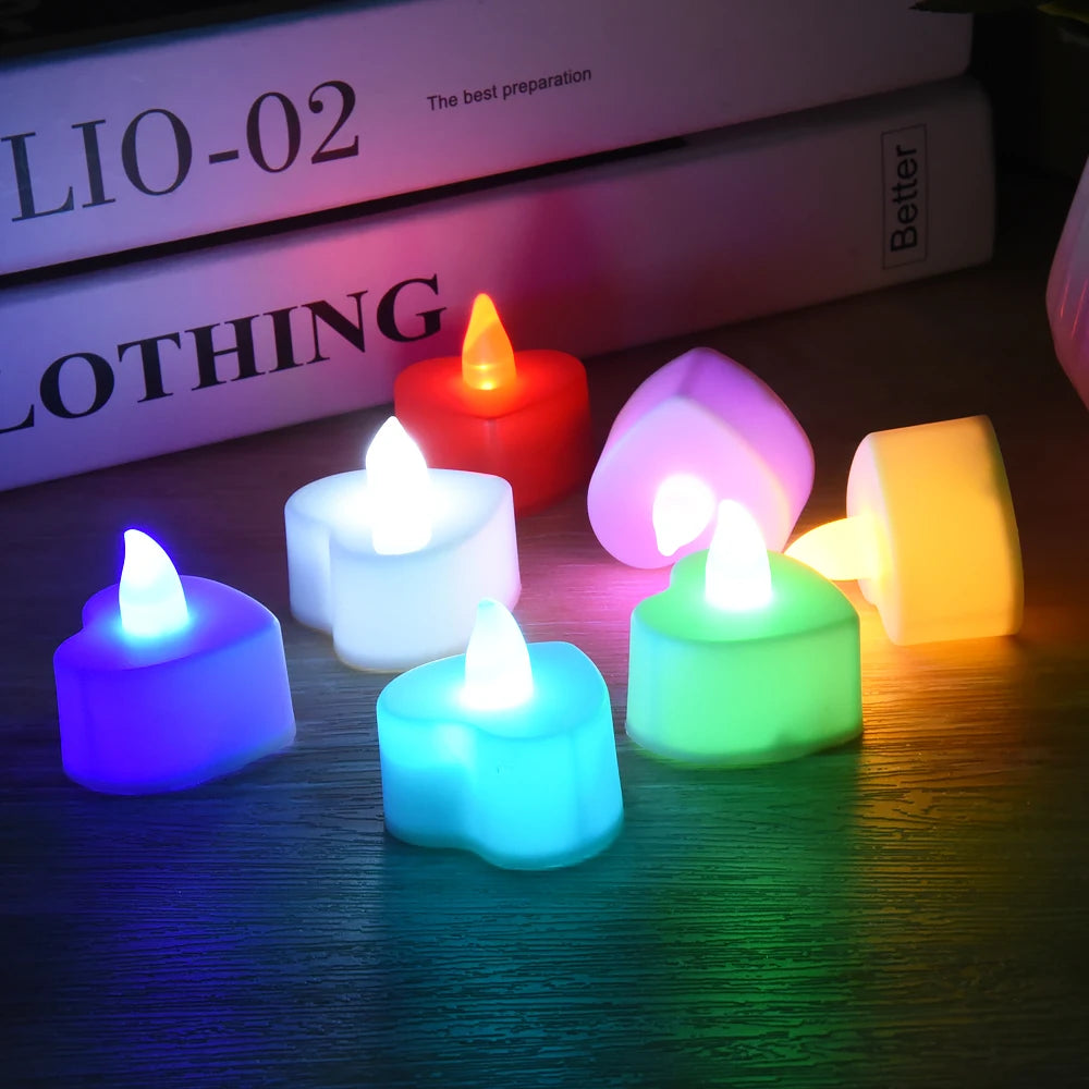 A collection of colorful, heart-shaped LED tealight candles glowing in various shades of pink, orange, yellow, and blue.