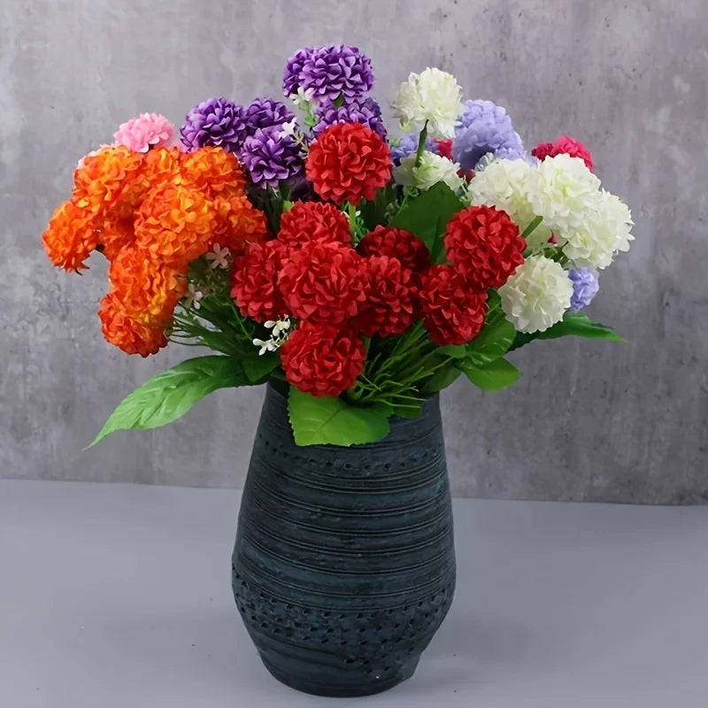 Un bouquet d'hydrangées artificielles vibrantes avec des grappes de fleurs orange, rouge, violette et blanche dans un vase fo