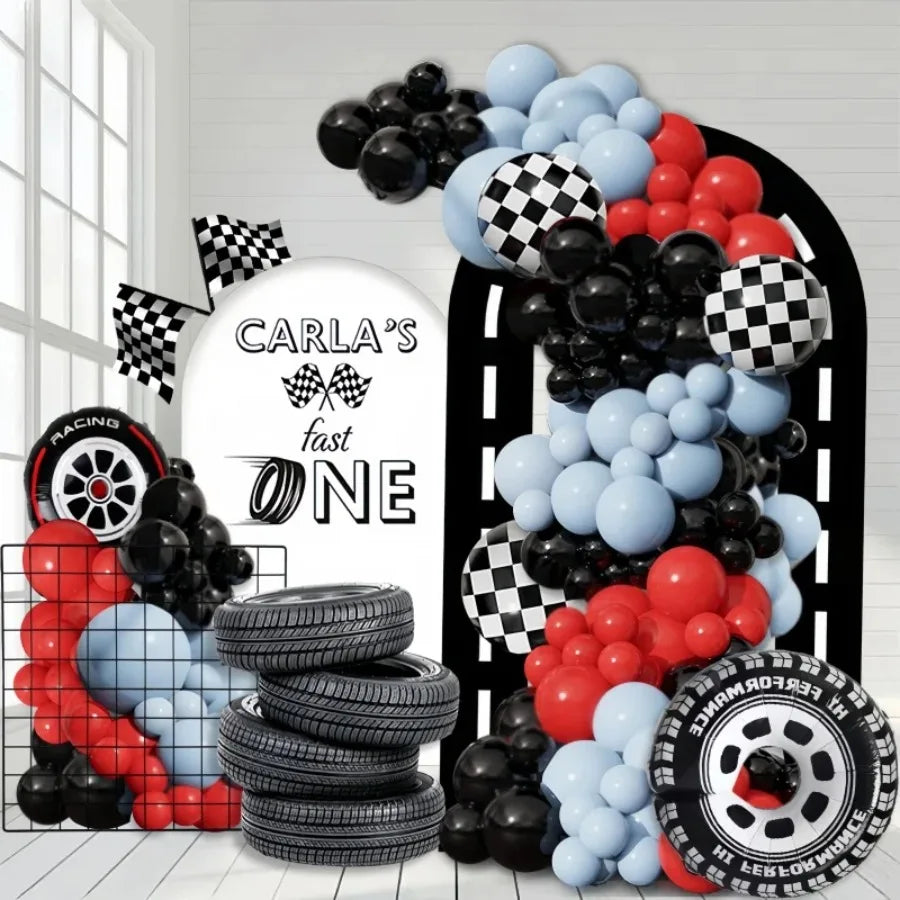 A balloon arch set featuring black, red, and blue balloons alongside stacked tires.