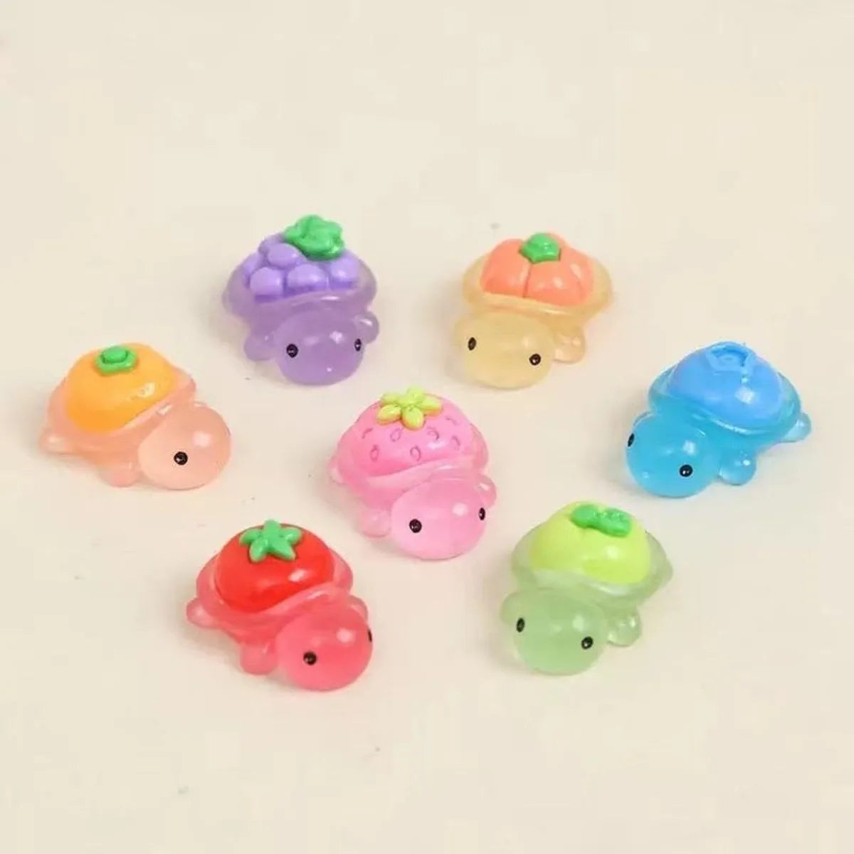 A collection of glow-in-the-dark fruit turtle resin charms in various colors like purple, yellow, pink, and blue.
